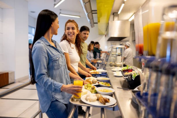 Colaboradoras sonriendo mientras se sirven la comida en un comedor industrial